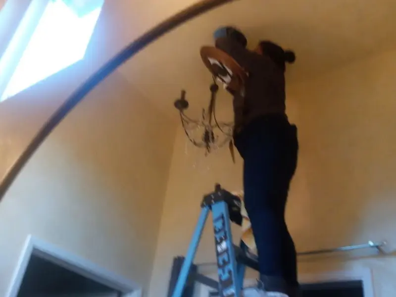 Electrician installing a chandelier in a Anderson Creek residence